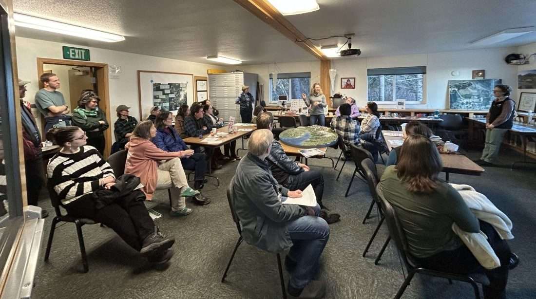 People sitting in a room listening to speaker.