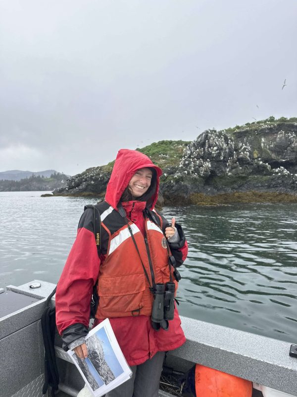 Woman in life jacket next to Gull Island with Kittiwakes