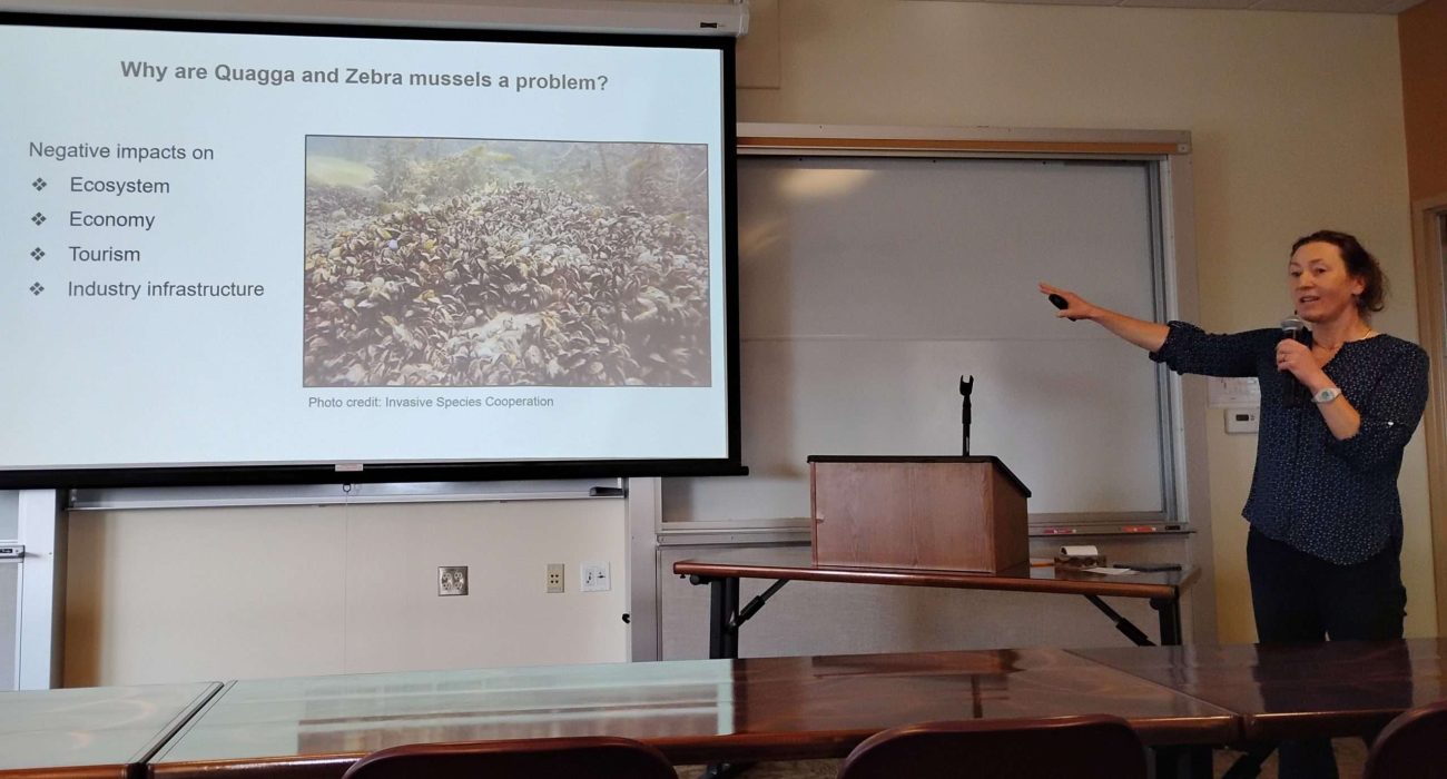 Presenter shows invasive freshwater mussel infestation on slide