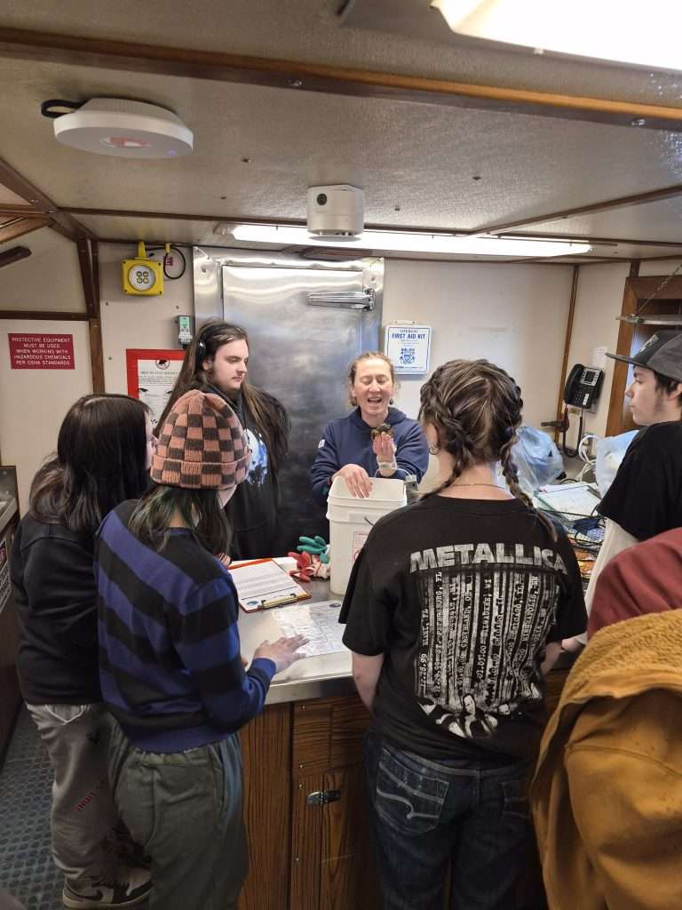 Students and KBNERR staff in lab gathered around a table