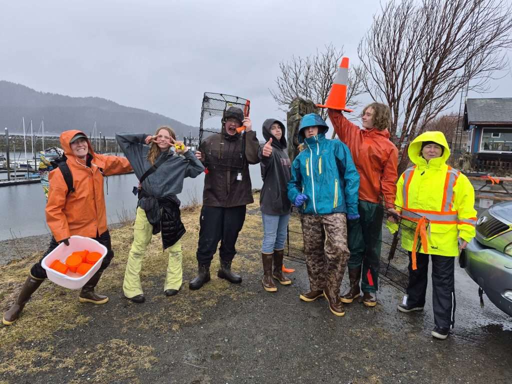 Students in raingear on shore line with field gear.